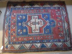 A red ground Kazak rug with stepped geometrical central medallion in cream, sea green,