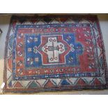 A red ground Kazak rug with stepped geometrical central medallion in cream, sea green,