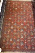 A red ground Kazak rug with all over repeating pattern in a salmon pink, burnt orange,