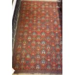 A red ground Kazak rug with all over repeating pattern in a salmon pink, burnt orange,