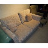 A modern two seat sofabed with gold and terracotta floral decorated upholstery,