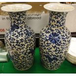 A pair of Chinese blue and white vases decorated with scrolling foliage and flowers on a white