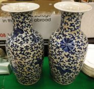 A pair of Chinese blue and white vases decorated with scrolling foliage and flowers on a white