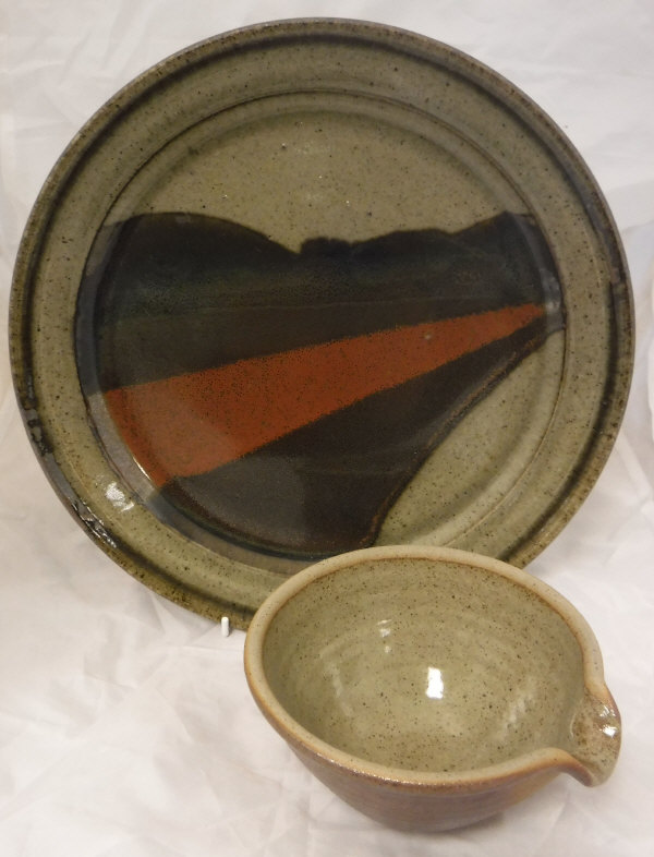 A John Leach Studio Pottery plate on a beige ground with brown red and brown striped flash,