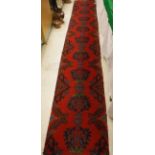 Two sections of Donegal type carpets, the red ground set with repeating green and blue motifs,