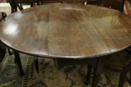 A George III mahogany oval drop-leaf dining table on turned tapering legs to heavy pad feet