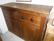 A pine dresser base with two drawers above two cupboard doors raised on a plinth base