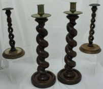 A pair of carved wooden barley twist candlesticks with brass candle holders and drip trays and