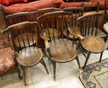 A Harlequin set of six stick back beech and elm kitchen chairs to include one carver,