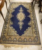 A midnight blue ground Kashan rug with central light oatmeal ground medallion in cream, pale pink,