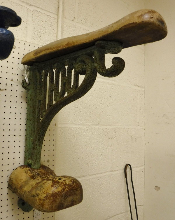 A painted cast iron wall-mounted saddle rack with wooden mounts