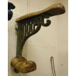 A painted cast iron wall-mounted saddle rack with wooden mounts