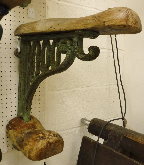 A painted cast iron wall-mounted saddle rack with wooden mounts