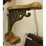 A painted cast iron wall-mounted saddle rack with wooden mounts