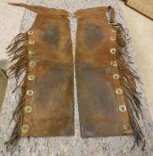 A pair of circa 1930's vintage authentic American leather chaps with tassels and metal trim,