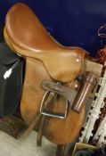 A general purpose Hayes of Cirencester brown leather saddle with stirrups,