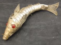 A white metal articulated fish in the Medina style with red paste eyes