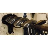 A painted cast iron wall-mounted saddle rack with oak mounts