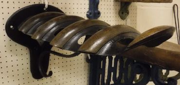 A painted cast iron wall-mounted saddle rack with oak mounts