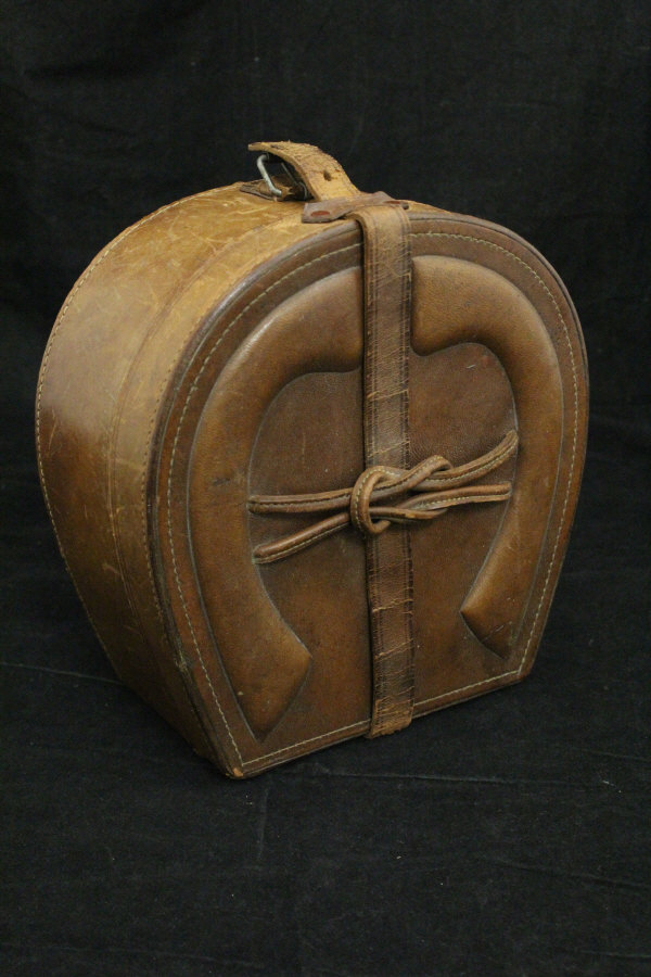 A vintage leather collar box in the form of a horseshoe with embossed horseshoe decoration to top,