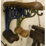 A painted cast iron wall-mounted saddle rack with wooden mounts,