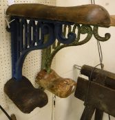 A painted cast iron wall-mounted saddle rack with wooden mounts,