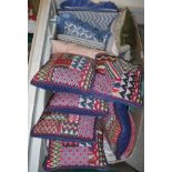 A box containing assorted woven scatter cushions in dark blue, red and pale blue and cream ,