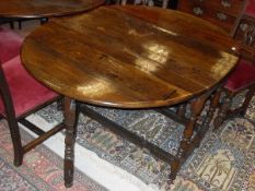 An oak oval gate leg drop leaf dining table in the circa 1700 manner with end drawer raised on