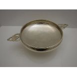 A George V silver hammered bowl in the form of an over-sized quaiche with open lug handles raised