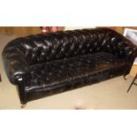 A late Victorian buttoned leather upholstered Chesterfield sofa on turned legs to brass caps and