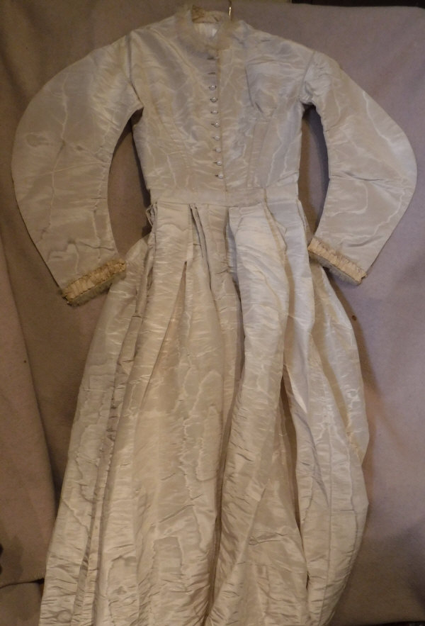 A mid Victorian cream moire silk wedding dress with ribbon and net detail,