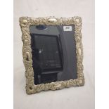 A modern silver photograph frame with embossed scrolling foliate decoration by Carrs