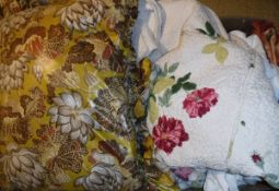 A box containing assorted scatter cushions, a bedspread with floral sprays on a cream ground,