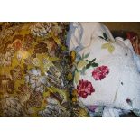 A box containing assorted scatter cushions, a bedspread with floral sprays on a cream ground,