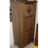 An Arts and Crafts oak single panel door wardrobe and matching cupboard with drawer above cupboard