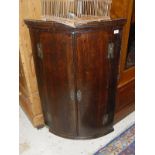 A 19th Century oak and cross banded bow front wall hanging corner cupboard with two doors opening