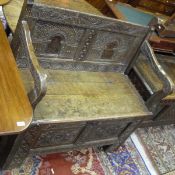 An oak box seat hall settle with carved decoration in the 17th Century manner CONDITION