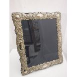 A modern silver photograph frame with embossed scrolling foliate decoration by Carrs