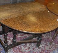 An 18th Century oak oval gateleg drop leaf dining table with end drawer on turned legs to block