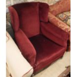 A circa 1900 upholstered wing back scroll armchair on squat bun feet to castors