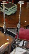 A pair of 20th century wrought iron floor standing candle holders on scrolling tripod supports