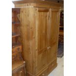 A pine two door wardrobe with two drawers on a plinth base