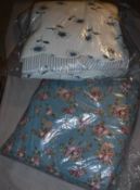 A modern double bed throw with two matching cushions, the white ground with blue floral stems,