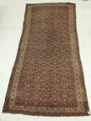 A Persian carpet, the central panel set with all over repeating floral design on a red ground,