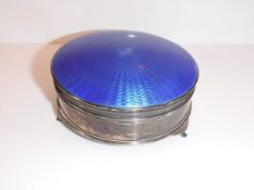 A George V silver and enamel decorated dressing table box of circular form with engine-turned