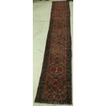 A Persian runner, the central panel set with all over floral decoration on a salmon pink ground,
