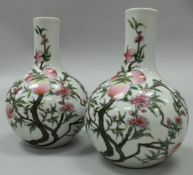 A pair of Chinese porcelain gourd-shaped vases decorated with flowering and fruiting peach trees,