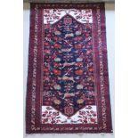 A Persian rug, the central panel set with stylised bird and floral motifs on a black ground,