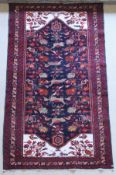 A Persian rug, the central panel set with stylised bird and floral motifs on a black ground,