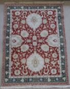 A near matching pair of Agra rugs, each set with flower head medallion decoration on a rust ground,